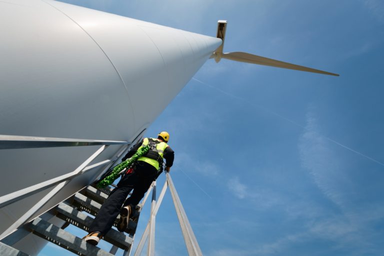 Wartungsarbeiter steht an einer modernen Windkraftanlage, Biddinghuizen, Flevoland, Niederlande