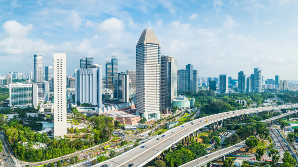 Aerial panorama over the towering skyscrapers and busy highways of downtown Singapore surrounding Marina Bay.