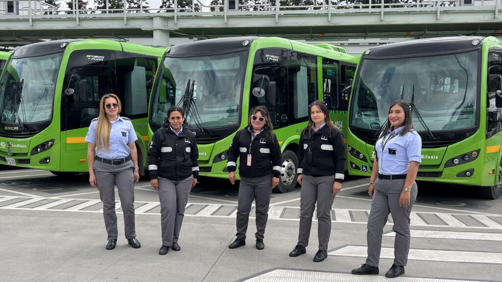 Women e-bus drivers in Bogotá who are part of the La Rolita e-bus training programme led by the City of Bogotá. The image shows five women standing in front of green e-buses.
